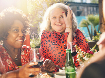 Two women and a man dinning and drinking wine