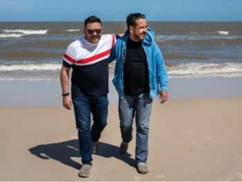 A gay couple walking on a beach in Uruguay