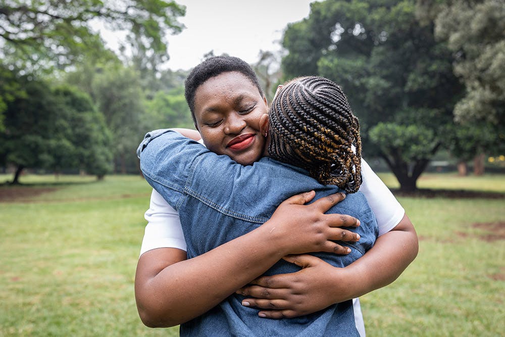 Woman living with HIV hugging her friend in Kenya