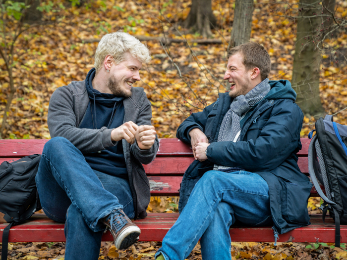 Two men sitting on a bench chatting and smiling in Hamburg