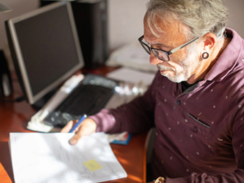 older man living with HIV sitting at a desk