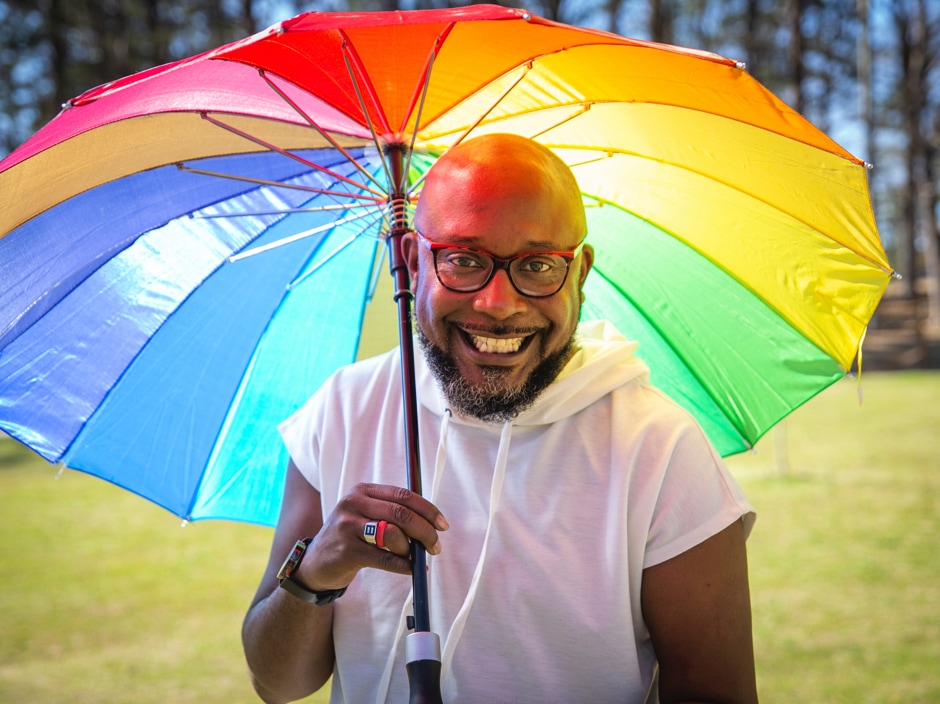 Close-up of man with rainbow umbrella.