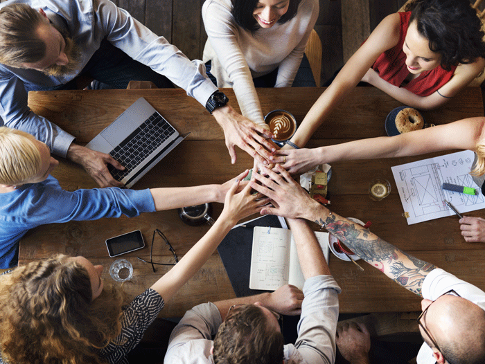 Grupo de personas trabajando y juntando las manos en el centro