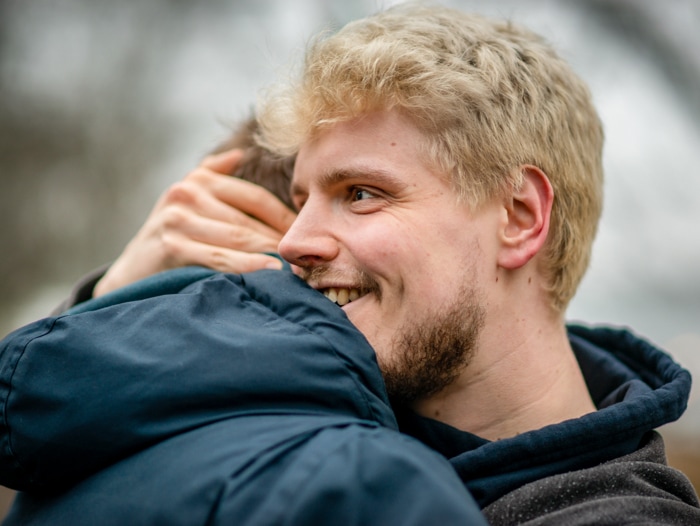 Uomo biondo che vive con HIV che abbraccia un suo amico fuori da un parco ad Amburgo, Germania