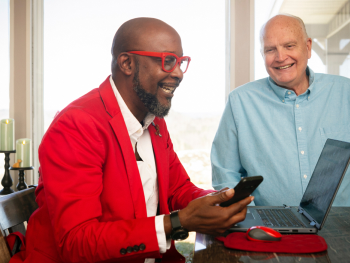 Uomo di colore che vive con HIV al lavoro da casa con il PC portatile assieme al suo partner