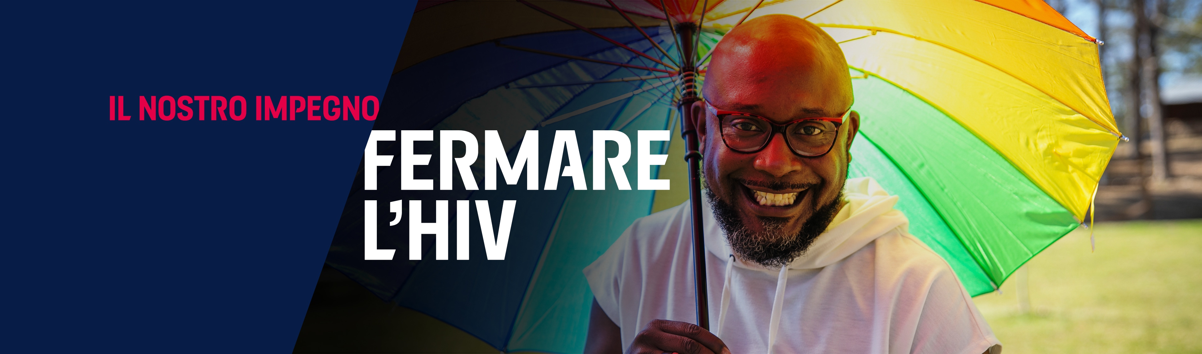 Uomo di razza nera che vive con l'HIV negli Stati Uniti sorride e tiene in mano un grande ombrello con i colori dell'arcobaleno